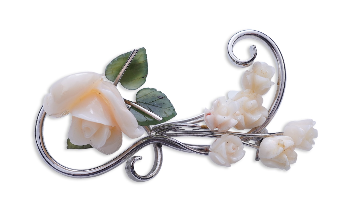 A white coral and nephrite brooch, designed as a spray of roses in carved white coral with nephrite leaves, on a scrolled white gold mount, length 5.5cm, stamped 14K, gross weight 11 grams